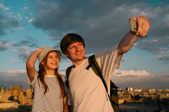 Man and girl taking a selfie over a historic city of Bukhara