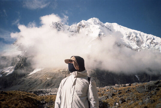 Person Stands in Front of Snow-Covered Mountains in Cusco