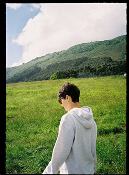 Person walking in green mountain meadow on sunny day
