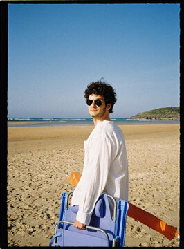Young man carrying beach chair at ocean vacation