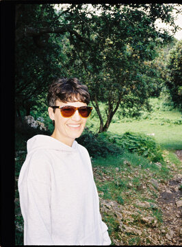 Woman smiling wearing sunglasses outdoors in nature