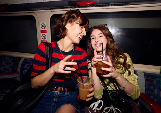 Mother and daughter enjoy drinks on a train ride in the city