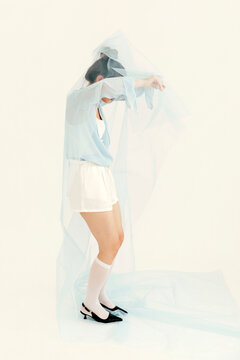 Woman posing with light blue sheer fabric