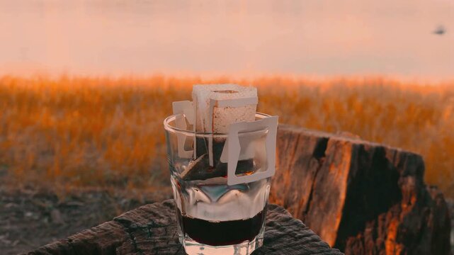 Close up of pour-over coffee extraction with blurred birds flying over misty lake at dawn