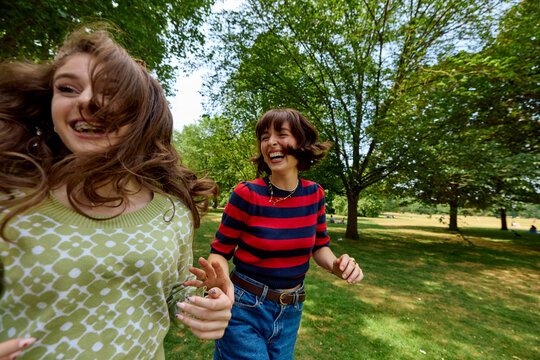 Mom and daughter run and laugh at the park.