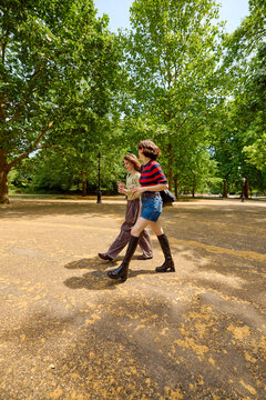 Friends walk through a landscaped area, enjoying sunny day