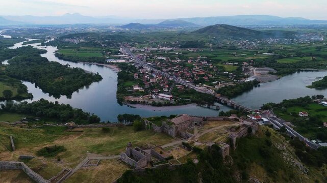 wide aerial scenic view of Shkod&euml;r, Albania, drone fly above Rozafa Castle ruins with mountains hill and river at sunset
