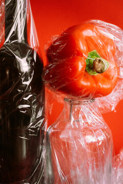 Red bell pepper and glass bottles wrapped in plastic