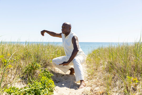 Black man athletic doing Tai Chi on Beach 