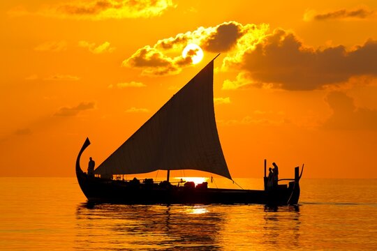 Traditional Maldivian dhoni sailing at sunset
