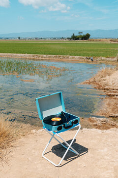 a record player on a folding stool stands alone in the midday heat