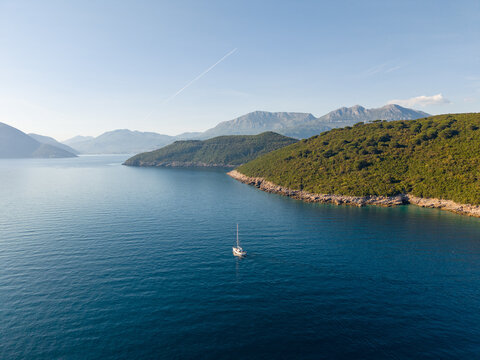 Alone yacht sailing Near Coastline With Mountains and Clear Sky