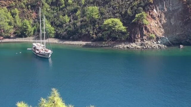 Experience the tranquil beauty of Fethiye Turkey as a graceful sailboat drifts on the deep azure sea.
