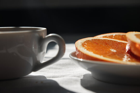 Tea in a cup served with oranges on a table