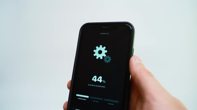 Hand holding smartphone with software update downloading on dark screen close-up 
