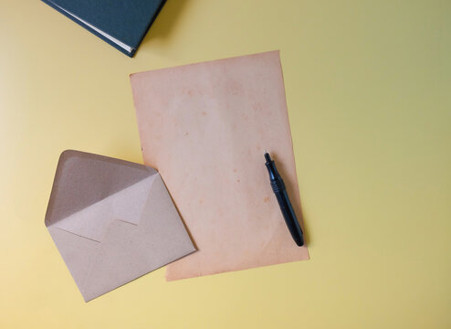 Old paper with envelope and book on color background.