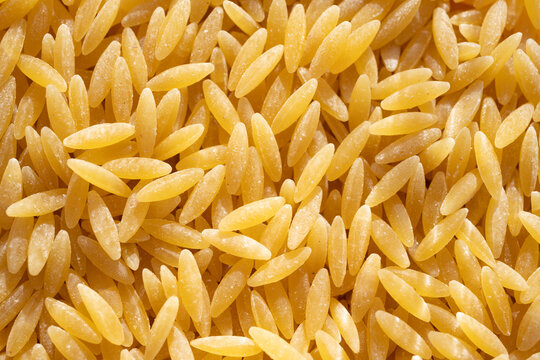 Close-Up of Dry Orzo Pasta as Golden Food Background