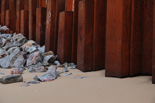 Rusty Steel Sheet Piling with Riprap Rocks on Beach