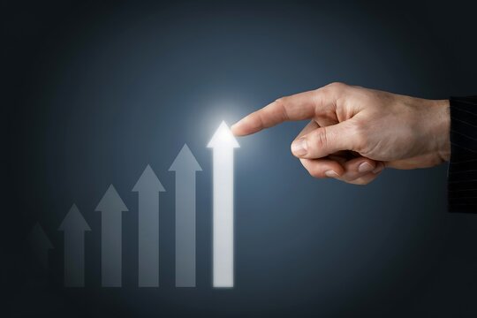 Business hand pointing at rising digital arrow graph representing growth and success