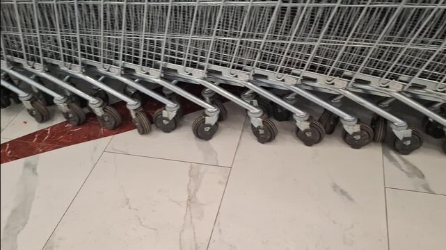Shopping carts lined up in a store parking area. Retail shopping, consumer transport, supermarket entrance, everyday commerce.