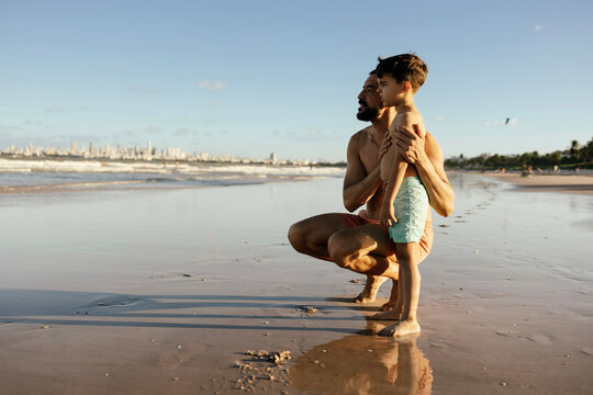 Father And Son Talking On Sunset Beach At Low Tide - Family Bonding And Summer Vacation
