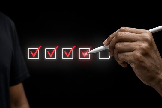 Close up of a hand using a white stylus to select check marks on a digital interface checklist