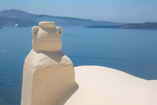 A white sculpted vase stands against the blue Aegean Sea in Santorini, Greece, capturing the minimalist elegance of Cycladic architecture and Mediterranean calm.