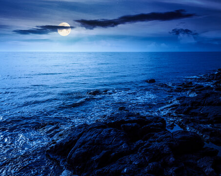 sea coast with stones and rocks at night. summer vacation background. full moon over seascape with rough terrain. fantasy relaxing at the sea. mysterious coast of bulgaria