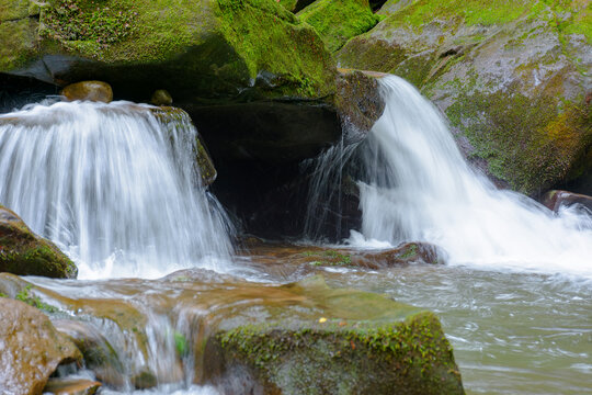 small waterfall closeup. beautiful cascade on the water stream with mossy rock