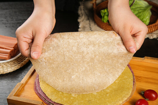 Hands Holding Fresh Whole Grain Tortilla with Vegetable Ingredients for Healthy Home Cooking
