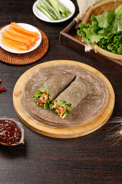 Whole Wheat Vegetable Burrito Wrap with Fresh Ingredients on Rustic Wooden Board