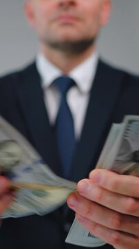 Formally dressed man is counting US Dollar bills, close-up.