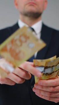 Formally dressed man carelessly throws Canadian Dollar bills towards the camera