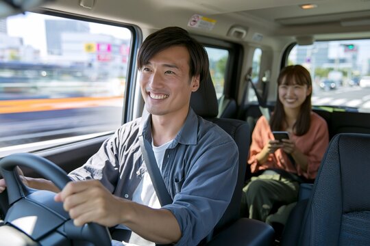 笑顔で運転する日本人男性とスマートフォンを持つ女性