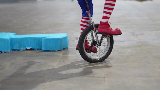 clown feet getting on a unicycle