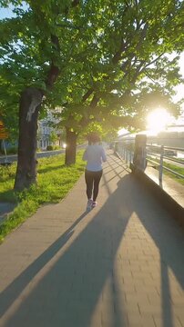 Caucasian woman runs along the embankment. Unusual view, filmed on FPV drone.