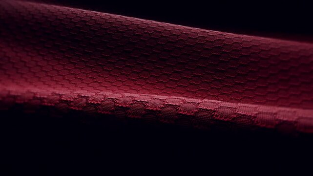 Widescreen loop of red technical mesh fabric flowing with a honeycomb weave pattern and dramatic lighting, seamless texture background for premium branding