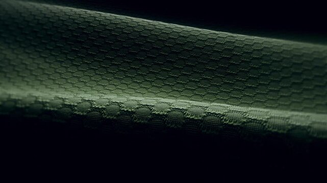Widescreen loop of dark green technical mesh fabric with a honeycomb weave pattern, moody night-vision style texture for website and desktop backgrounds