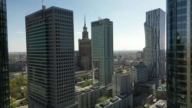 Aerial footage of Warsaw city center skyscrapers, modern office towers, traffic, urban density and clear daytime skyline views.