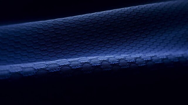 Widescreen loop of blue technical mesh fabric with a honeycomb weave pattern and dramatic lighting, seamless texture background for website and desktop backgrounds
