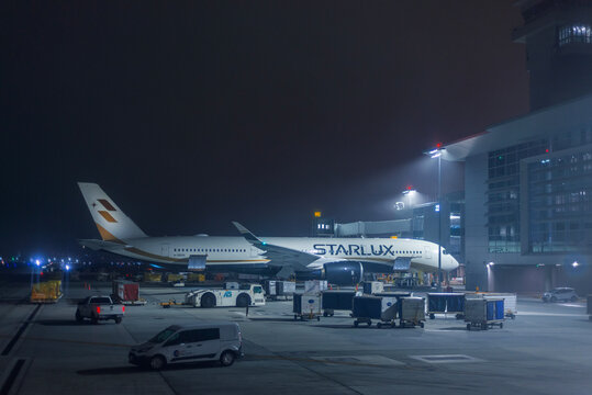 STARLUX Airlines aircraft parked beside an airport terminal during nighttime ground operations 
