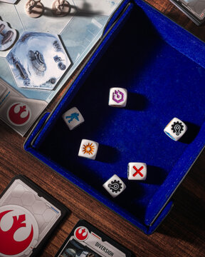 Dice arranged on a gaming mat in an overhead composition surrounded by Battle of Hoth game pieces and the Rebel symbol highlighting tabletop strategy and science fiction gameplay
