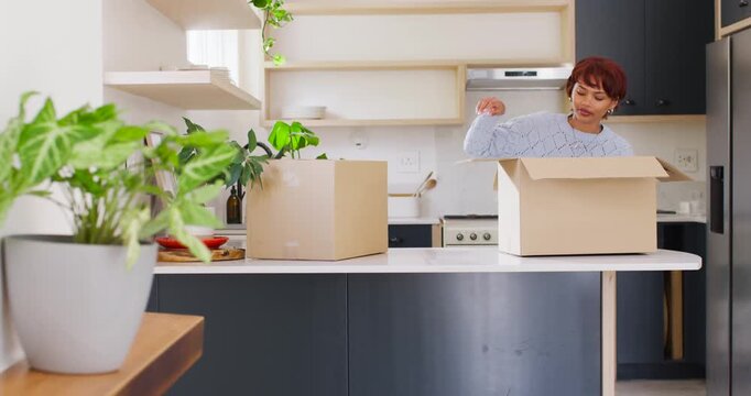 African American woman unpacking two boxes after delivery, inspecting white container on peninsula
