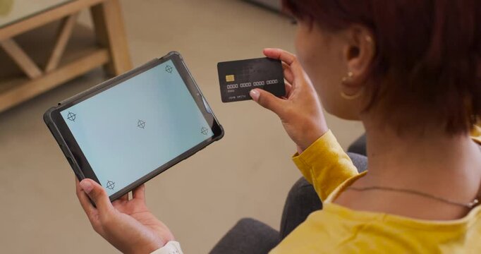 African American woman sitting on sofa holding tablet with markers, aligning black card for scan