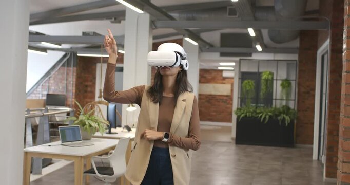 African American woman adjusting white VR headset raising finger and selecting items in office