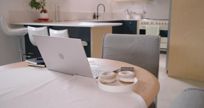 Camera is moving closer, revealing laptop and headphones on round table to show smartphone