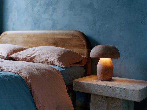 Sculptural mushroom table lamp beside bed in modern blue bedroom