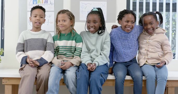 African American youths sitting on wood bench in classroom center youths laughing sparking hug