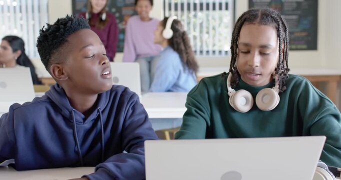 Diverse youth students two male students leaning asking typing on laptop working task trio smiling
