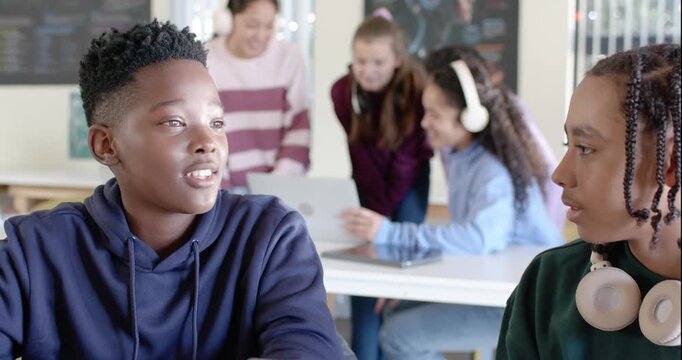 Classmates working in class with male youth speaking in navy hoodie, laptop, headphones, copy space